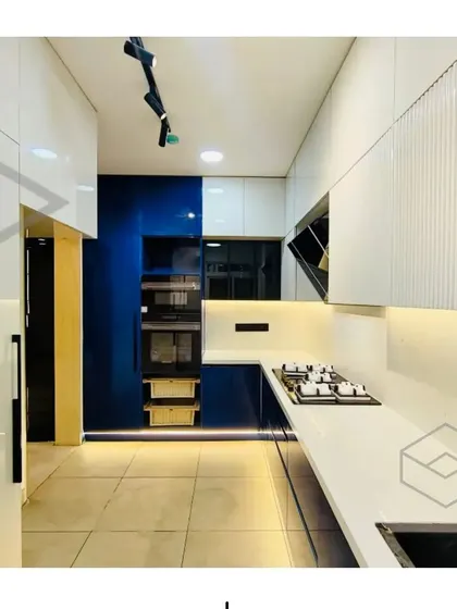 These images provide multiple angles of the stunning blue and white modular kitchen, showing details like the built-in oven tower, the fluted cabinet finish, and the overall clean and spacious layout.