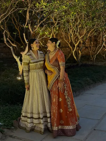A candid moment of laughter with a friend at a wedding. My striped Anarkali gown is a unique take on traditional evening wear.
