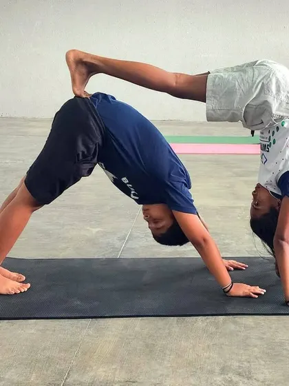 This creative partner pose combines a downward dog with a handstand press, demonstrating advanced balance, strength, and the trust between our campers.