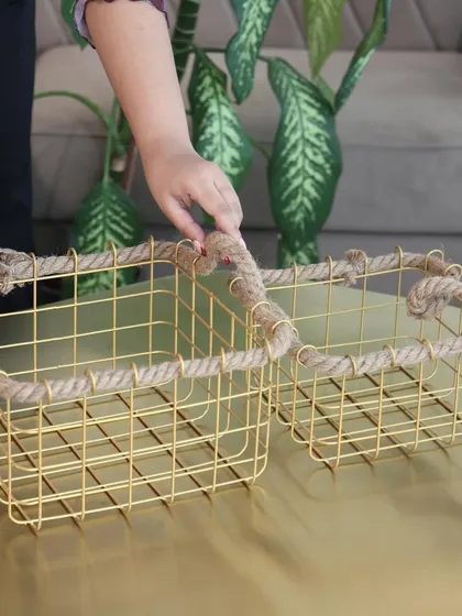 A pair of our gold wire and rope baskets, showing the two sizes available. They are perfect for creating a coordinated storage solution on a coffee table or shelf.