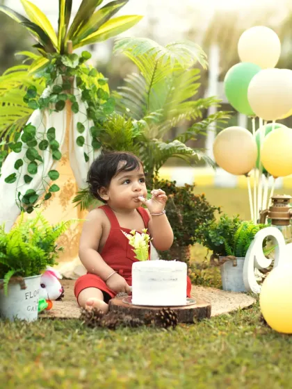 A moment of calm with the cake, surrounded by greenery and balloons. This outdoor setup combines nature with festive birthday elements.