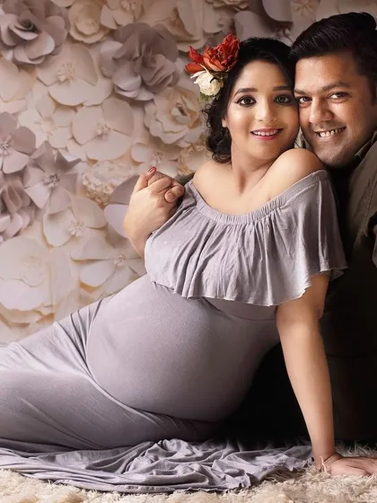 A cozy and loving portrait of a couple nestled together. The floral background and soft lighting create a warm and inviting atmosphere for this maternity session.