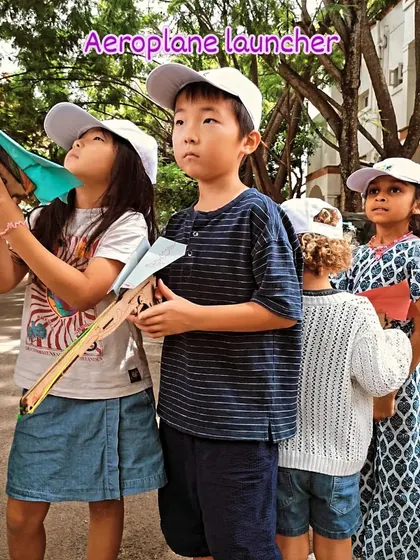 Ready for takeoff! Students line up with the aeroplane launchers they built, learning about aerodynamics and projectile motion.