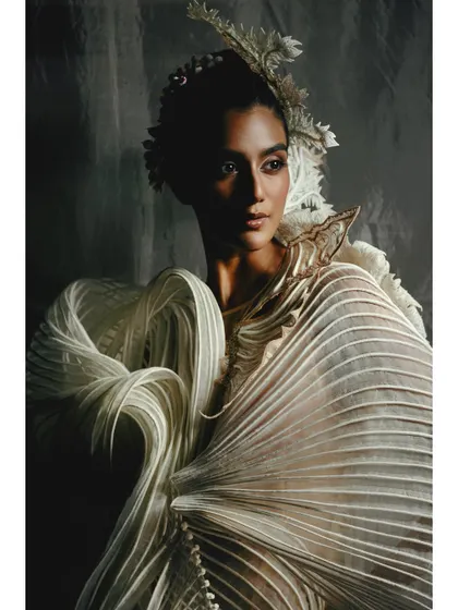 This shot highlights the sculptural quality of a pleated white gown from the Vaishali S collection. The lighting is carefully placed to carve out the garment's unique shape.
