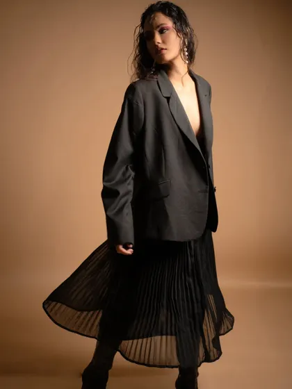 The movement of the pleated skirt is captured here, adding a soft, feminine element to the otherwise structured look.