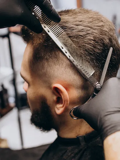 Precision and style define our men's grooming services. This image captures the detail-oriented process of a sharp, modern haircut, tailored to the individual.