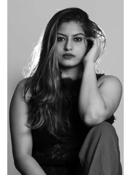 A moody and intense black and white studio portrait. The direct gaze and simple lighting create a powerful and captivating image.