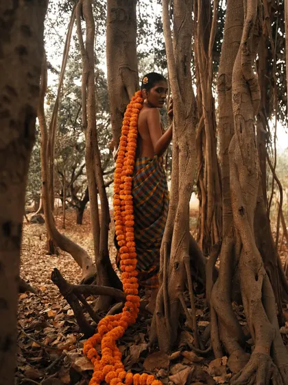 A wider version of the conceptual marigold hair shoot, showing the model interacting with the natural forest environment.