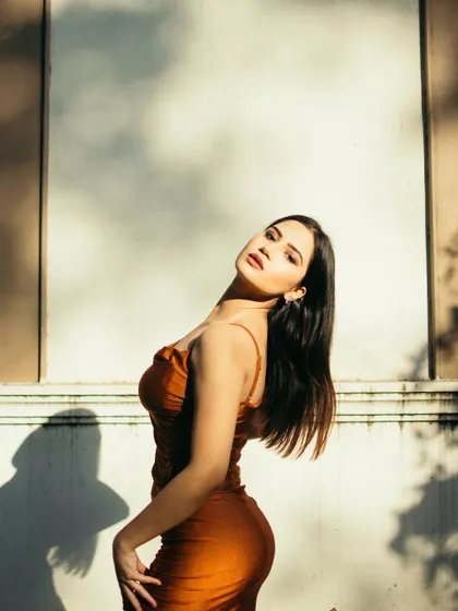 A portrait using the dappled light and shadows from a nearby tree. This technique creates a natural, artistic pattern on the wall, adding texture and interest to the shot.