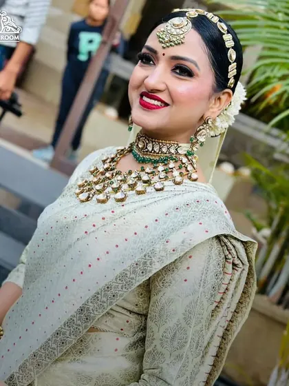 A happy, smiling shot of the bride. The bold red lip provides a beautiful contrast against her light-colored outfit and glowing skin.