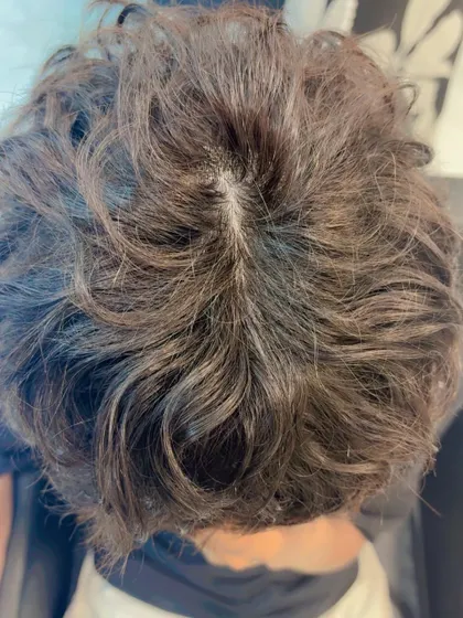 The top-down view of a short, curly wig. The scalp area is crafted to look completely natural, even with a textured hairstyle.