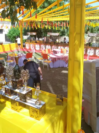A glimpse of an outdoor Haldi setup in progress. The vibrant yellow canopy and decor elements are ready to create a festive and sunny atmosphere for the celebration.