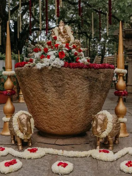 A traditional decor detail, featuring a large stone urli with a Ganesha idol, surrounded by floral arrangements.