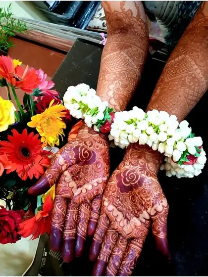 The rich color of the henna stain is beautifully contrasted with the colorful flowers in this photo from a happy client.