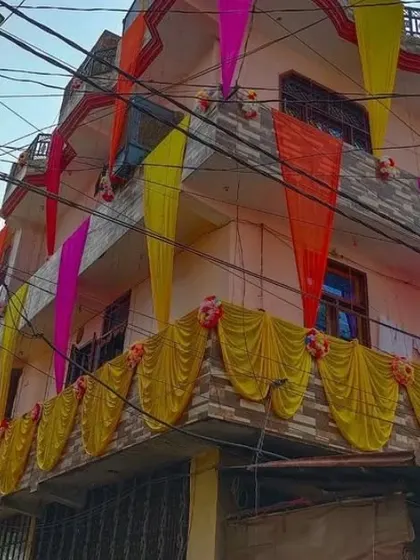 A house facade decorated with drapes in multiple colors, including pink, yellow, and orange.