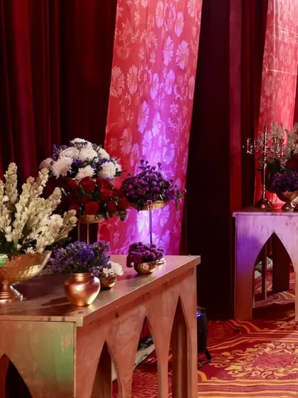 A closer look at the decor along the entrance walkway. Wooden console tables with arched designs held beautiful floral arrangements in brass vases, adding to the regal theme.