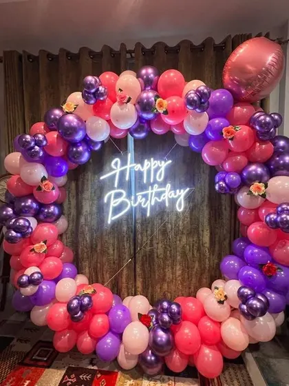 A full balloon ring in vibrant shades of purple and pink. This decoration is perfect for adding a pop of color to any birthday party, complete with a central neon sign.