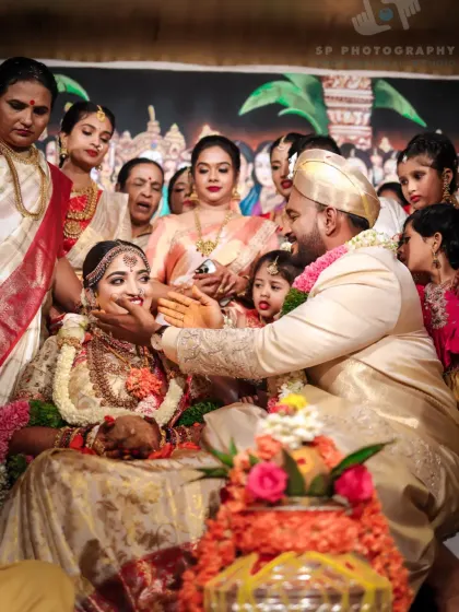 A beautiful moment from a traditional ceremony, with the groom lovingly interacting with the bride, surrounded by family. We capture the rich cultural heritage of the wedding.