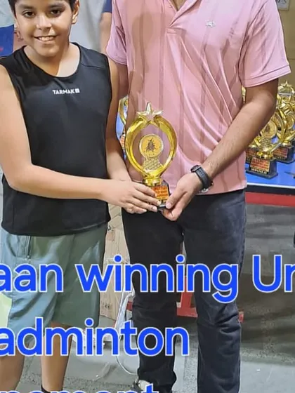 Coach presenting Yuvaan with his trophy for winning the Under-11 badminton tournament. We focus on developing competitive players from a very young age.