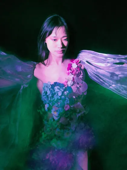 A portrait captured with a green light projection and motion blur, giving the impression of being underwater. The model's expression is serene, suggesting a peaceful surrender to the depths.