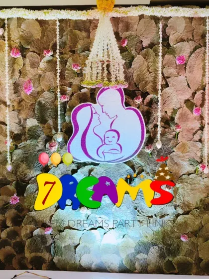 This unique backdrop was made with a mix of green foliage and delicate flowers. I added hanging jasmine strings and a custom cutout of a mother and baby to make it special.