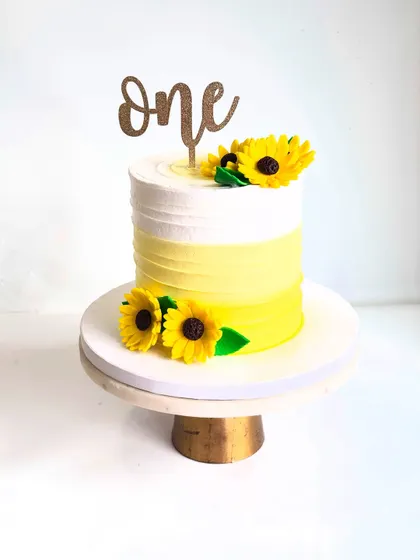 The ombre yellow stripes and handcrafted sunflowers make this a simple yet stunning cake for a first birthday.