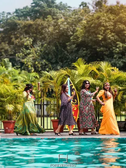 The bride tribe making a splash. A fun, candid shot of the bridesmaids and friends enjoying a poolside Haldi party, showcasing the celebratory atmosphere.