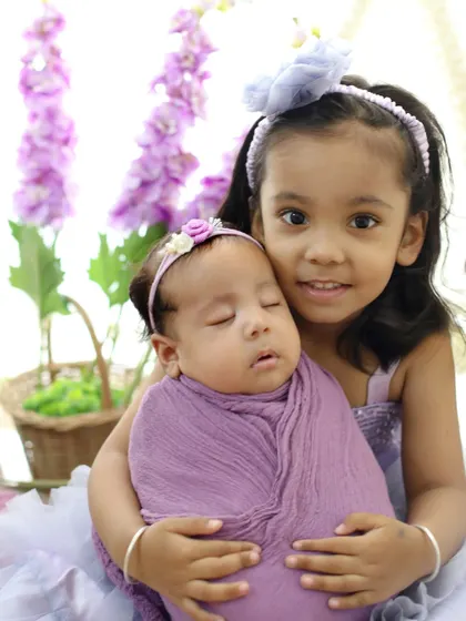 A proud big sister holds her new baby sibling. These are the moments that become cherished memories, showing the start of a beautiful friendship.