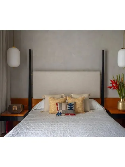 A frontal view of the custom four-poster bed, highlighting the symmetry of the design, the textured headboard, and the elegant pendant lights.