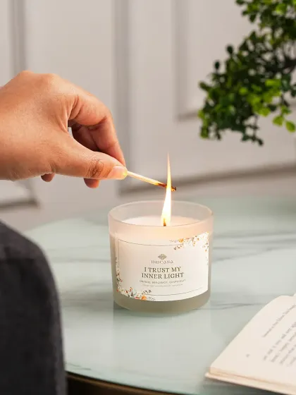 A lifestyle shot showing a hand lighting a scented candle, creating a relatable and aspirational moment. We believe showing products in a real-life context helps customers envision them in their own homes, which is key for conversion.