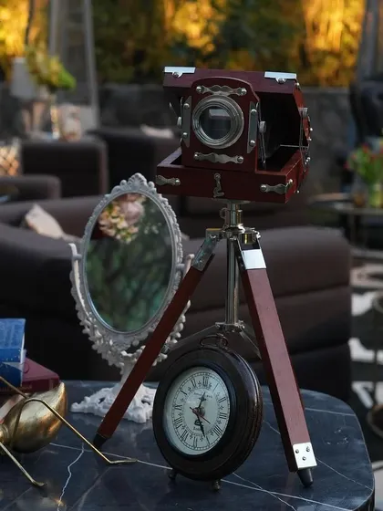 A vintage large-format camera on a tripod, paired with an antique clock and mirror, adds a touch of old-world charm to the decor.