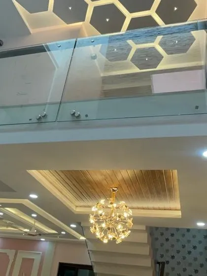 A unique view looking up through a glass floor to a hexagonal-patterned false ceiling on the upper level. This bold design choice allows light to travel between floors and creates a dramatic architectural feature.