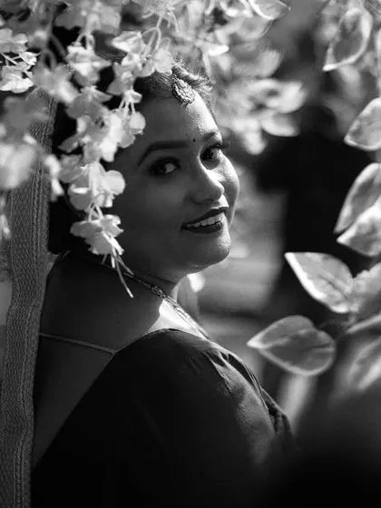 A black and white portrait of the bride looking over her shoulder with a gentle smile. Framed by leaves, this shot has a natural, candid, and artistic feel.