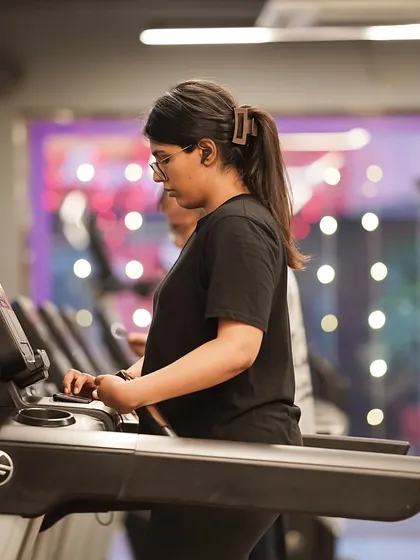 A member focuses on her run, using one of the many treadmills available in our spacious cardio section.