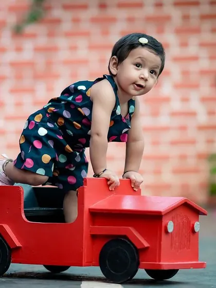 This little girl is having so much fun climbing on her red toy truck. Our props are designed to be interactive and fun for kids.