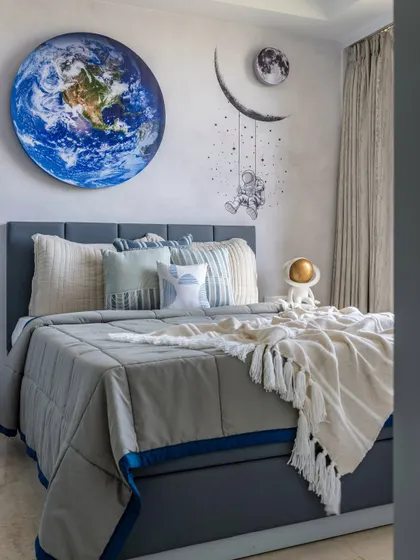A wider view of the space-themed bedroom, showing the layered bedding in calming blues and creams that keeps the room cozy and inviting for a little explorer.