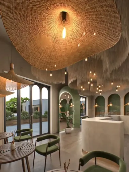 This view shows how the cafe opens up to an outdoor space, blurring the line between indoors and outdoors. The consistent use of natural materials and green tones creates a cohesive, tranquil environment.