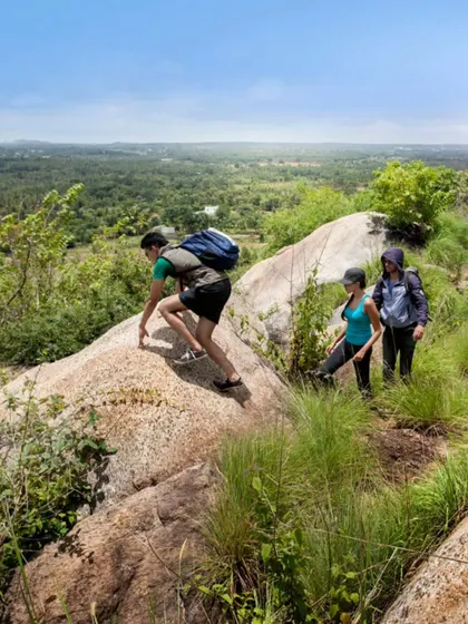 A group makes their way up a rocky trail, surrounded by the lush greenery of the monsoon season. Our treks are suitable for various fitness levels.