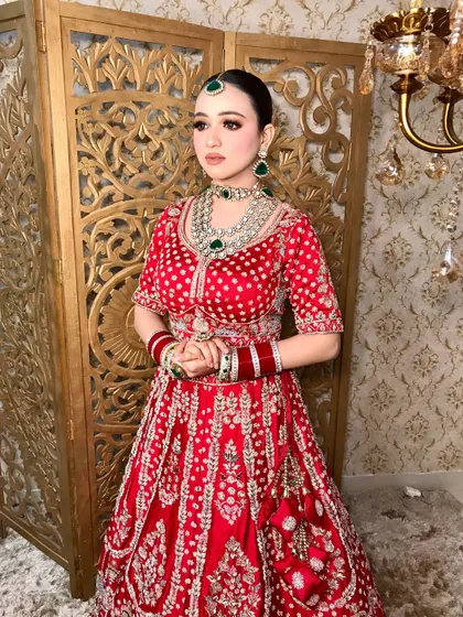 A full-length shot that captures the grandeur of the red lehenga and the elegance of the makeup.
