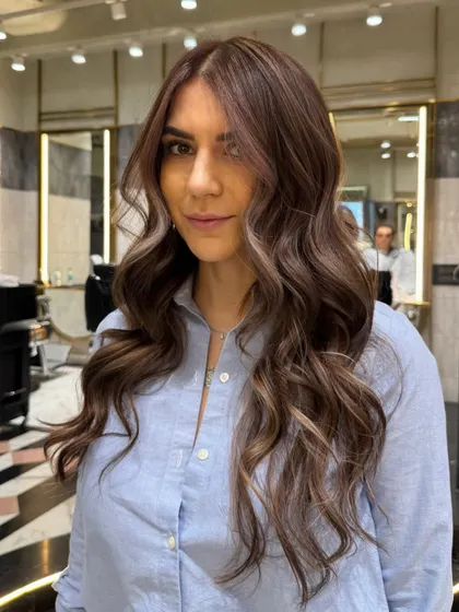 The finished look of an ash brown balayage, showcasing a happy client with beautifully blended, multi-tonal hair color.