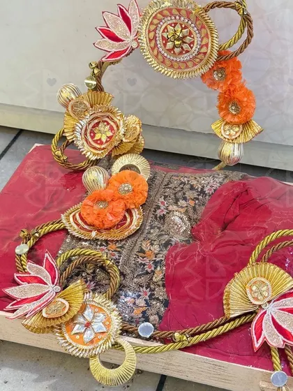 Another example of my detailed trousseau work. A deep red embroidered outfit is laid out on a wooden tray and adorned with handcrafted lotus and floral embellishments made from gota fabric.