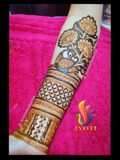 A bridal startup design for the arm, featuring a peacock among lotus flowers. This is a great way to begin a full bridal piece.