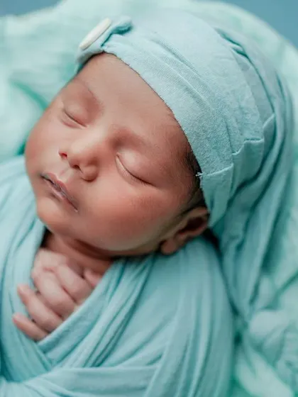 A peaceful sleep. This close-up on a swaddled baby's face captures the serenity and delicate features of a newborn.