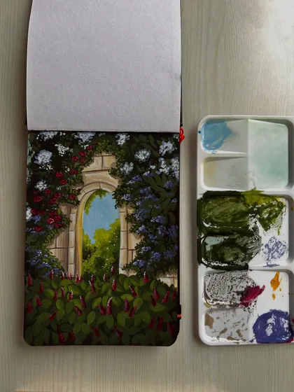A gouache painting of a secret garden archway, with my paint palette alongside.