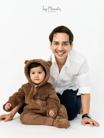 A sweet portrait of a father and his son. The adorable teddy bear outfit adds a touch of whimsy to this classic, seated pose, making it an unforgettable memory.