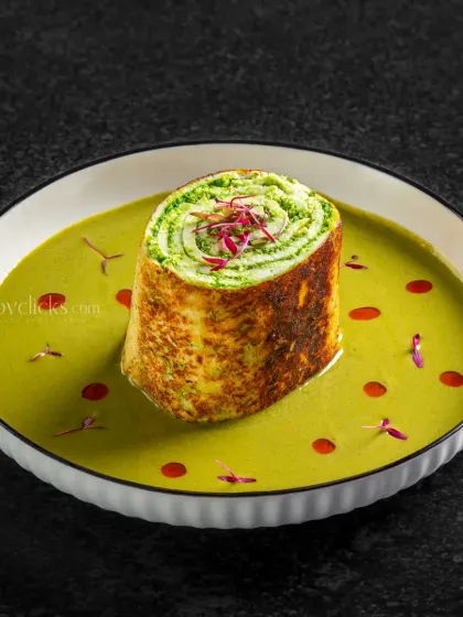 A creative pinwheel dish served in a vibrant green curry, showcasing modern culinary presentation.