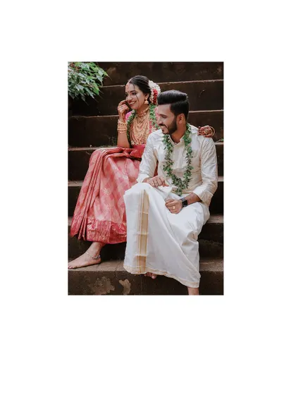 A relaxed and happy portrait of a couple sitting on stone steps after their wedding.