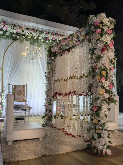 A close-up of the Nikah partition, intricately decorated with strings of white flowers and a border of colorful roses.