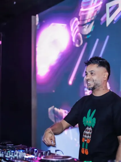 Here I am at the decks with a massive LED screen behind me displaying abstract, colorful visuals. This is a core part of my VJ service, turning the DJ booth into a visual centerpiece.