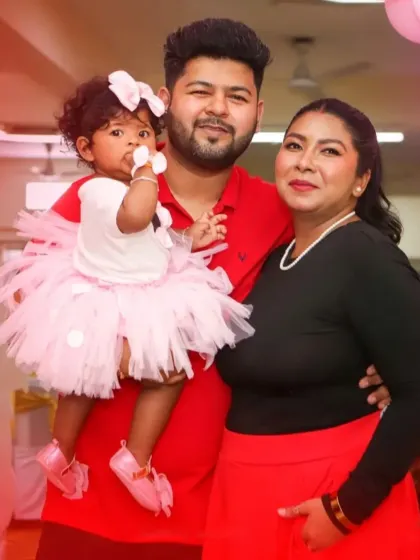 A classic family pose, capturing the parents and their little one during her birthday celebration.